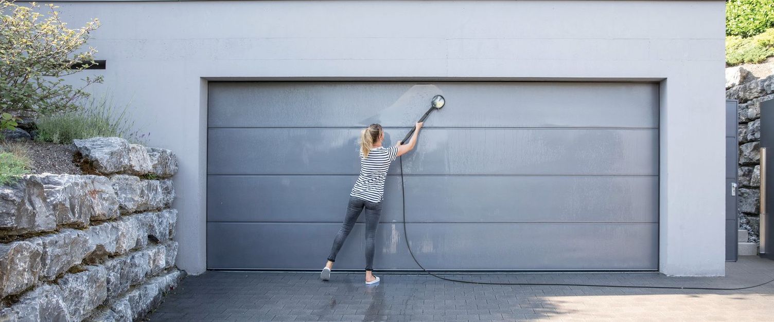 Cleaning the garage door A woman cleans her garage door with a Kärcher wash brush