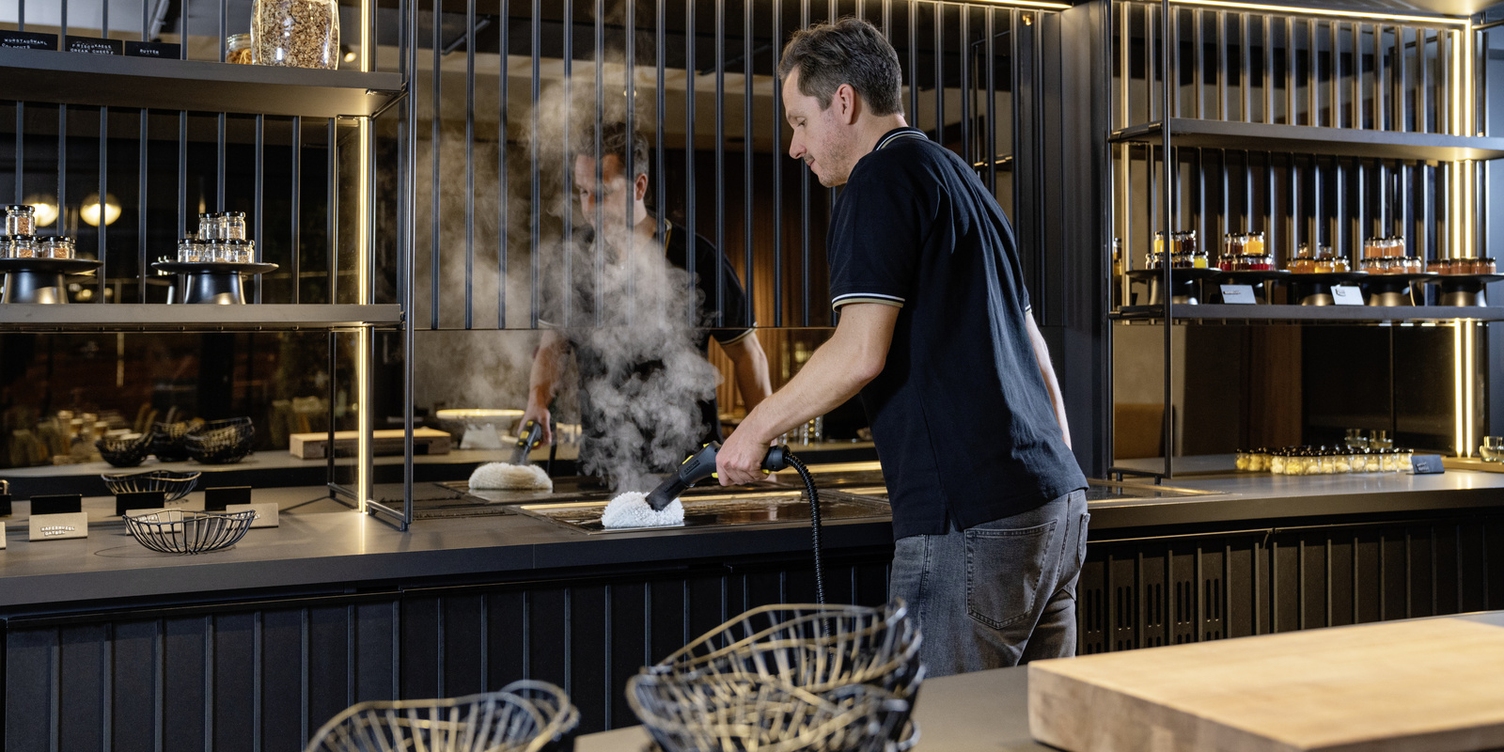 A person cleaning a kitchen surface with the Kärcher steam cleaner