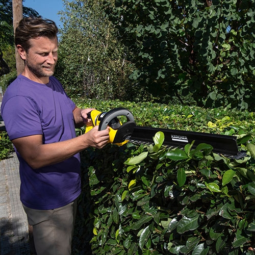 Hedge broom sweeps the cutting in front of the user