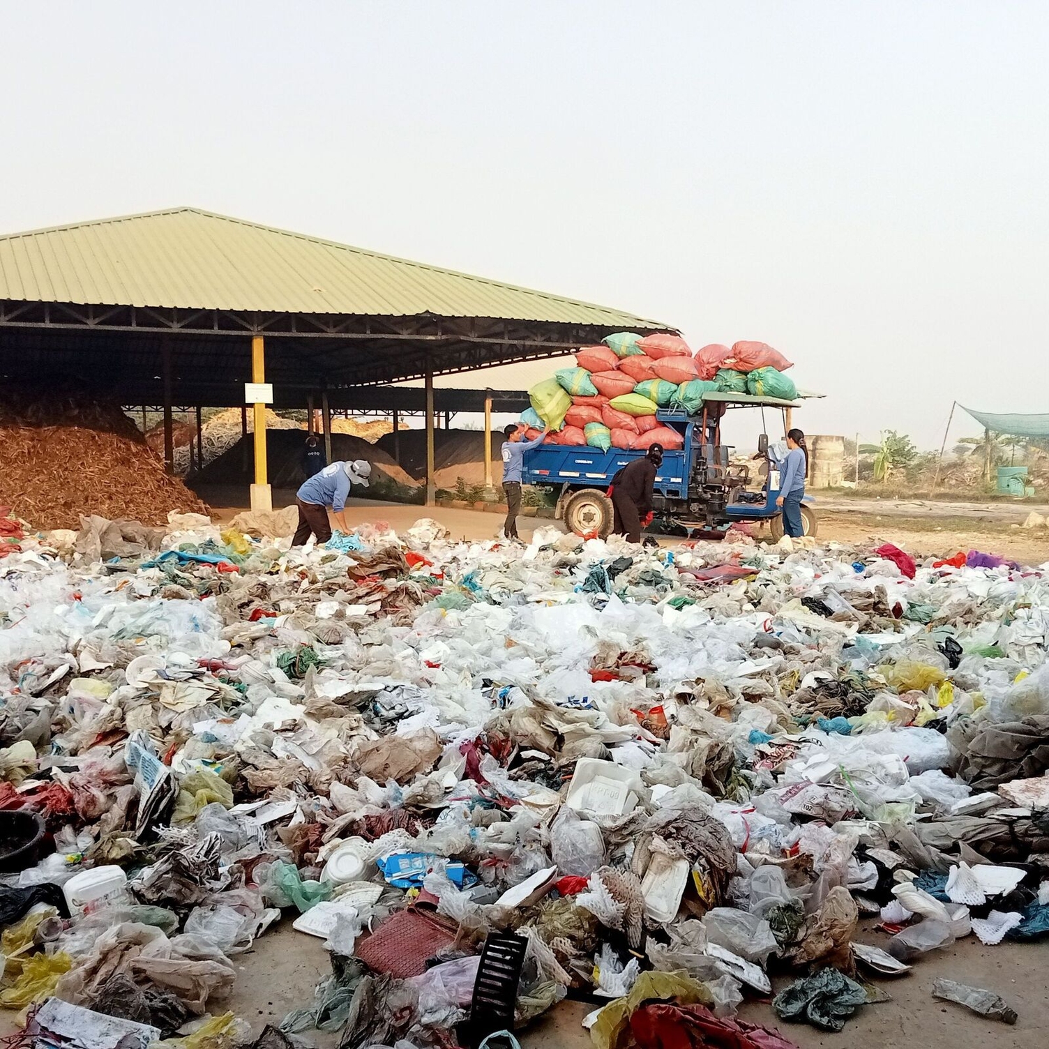A team loads a tuk tuk with bags of plastic waste