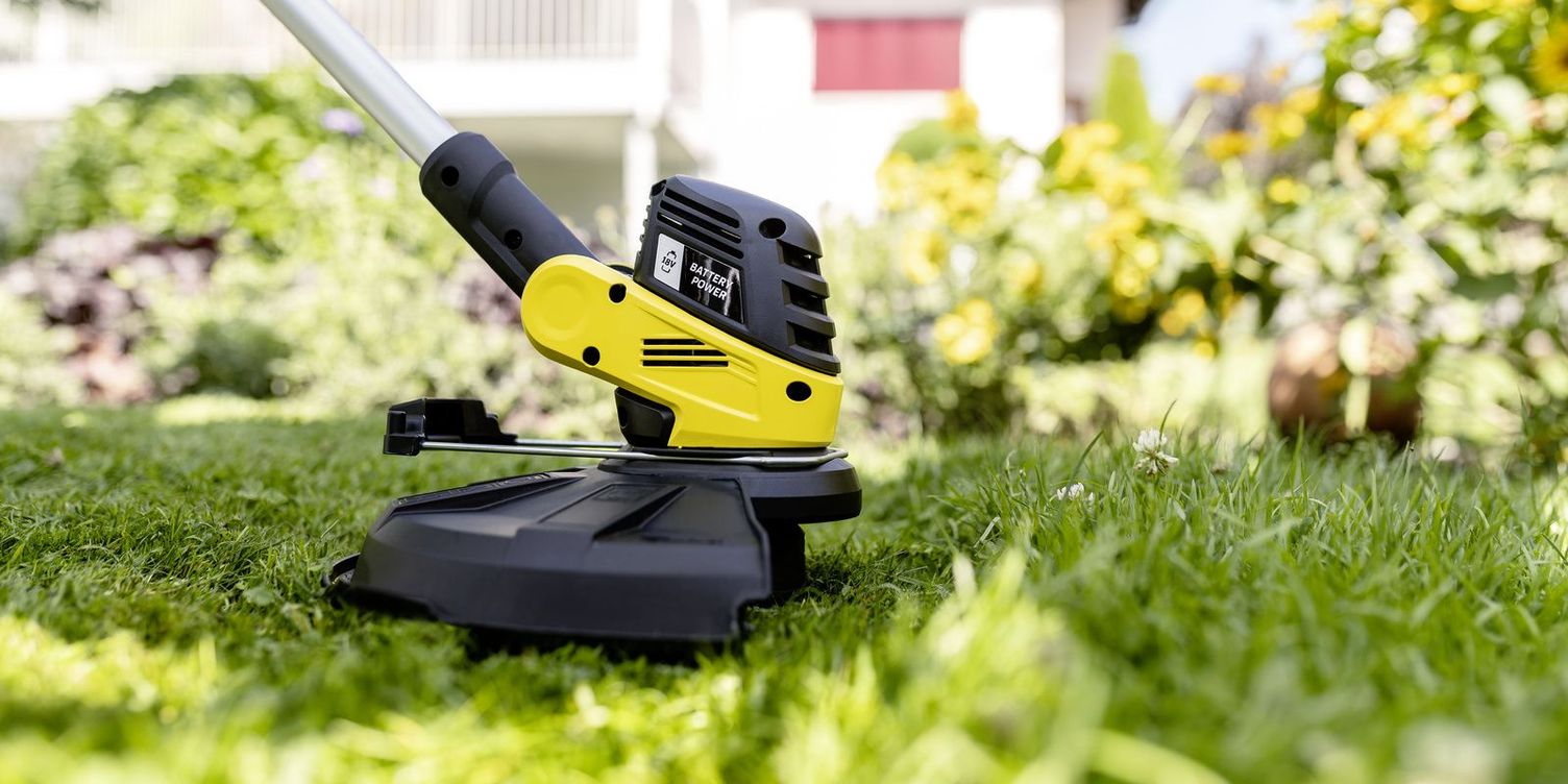 Close-up view: the Kärcher battery lawn trimmer with protective bonnet in action