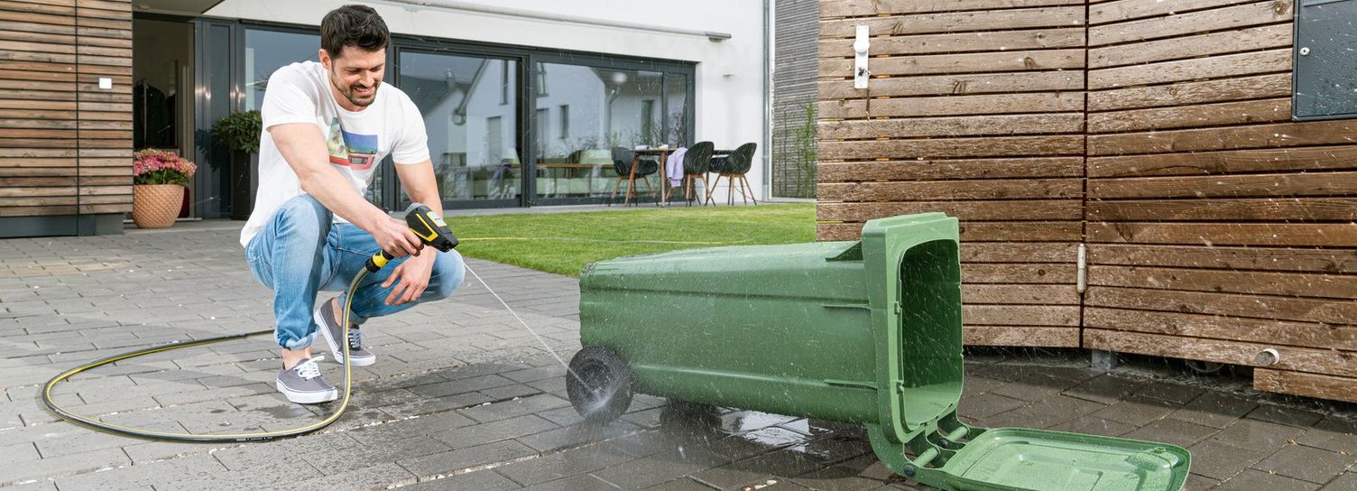 Clean the bin with the waterbooster A man cleans a bin with the Kärcher waterbooster