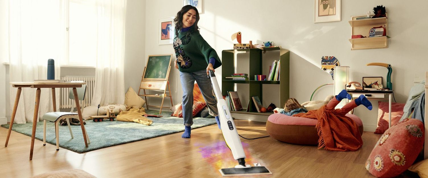 Karcher buharlı temizleyici ile ahşap zemini temizleyen kadın.