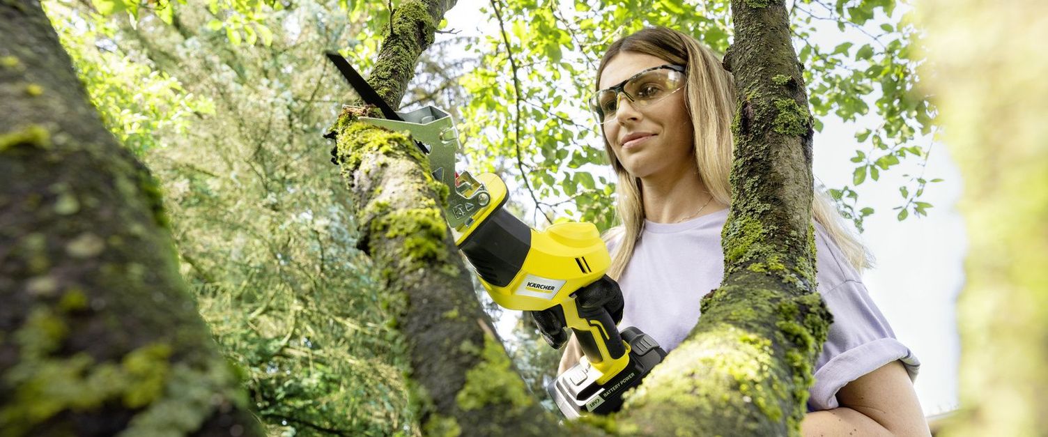 Person cutting branch with pruning saw