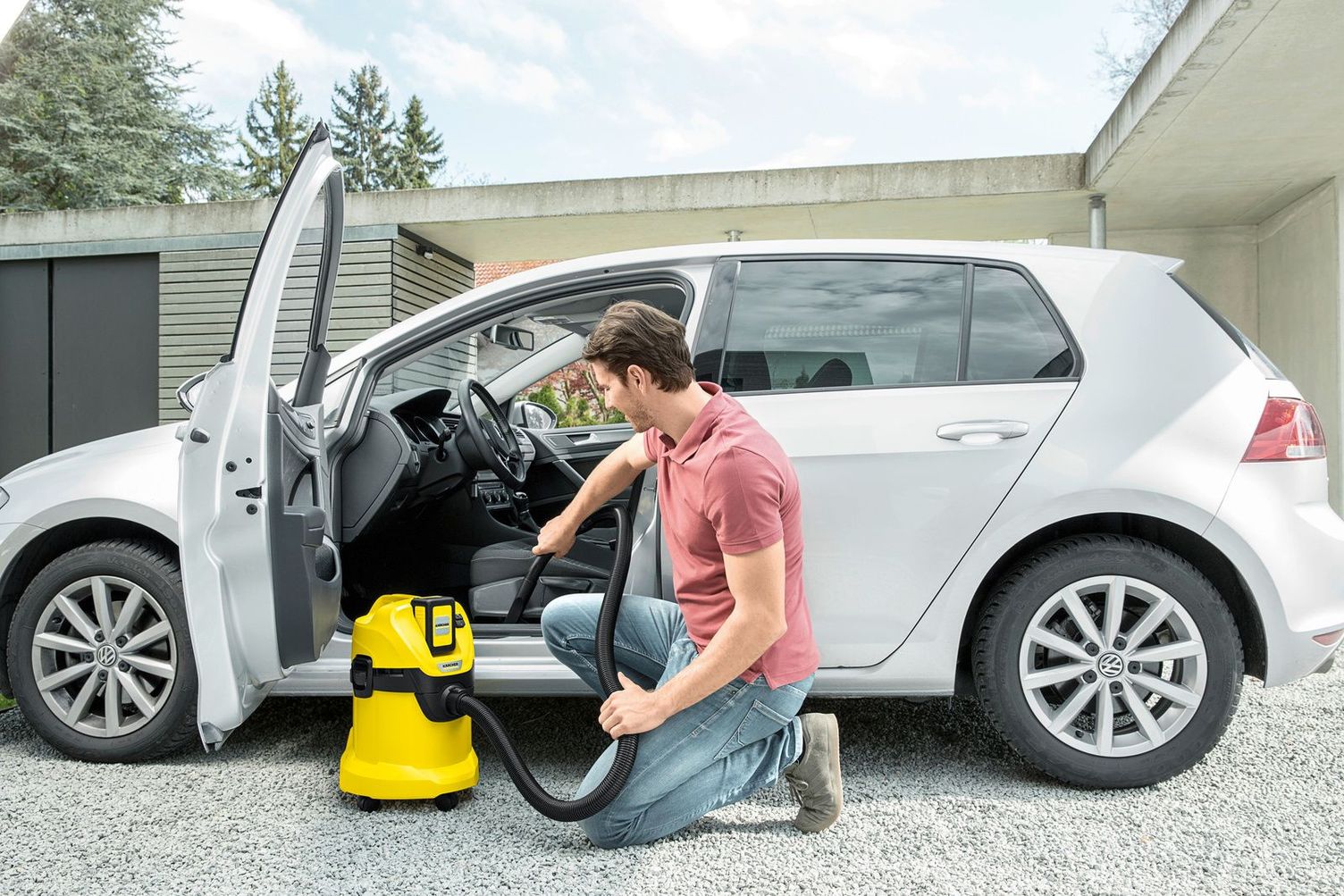 Person vacuums car with battery-operated wet and dry vacuum cleaner Kärcher battery-operated wet and dry vacuum cleaners
