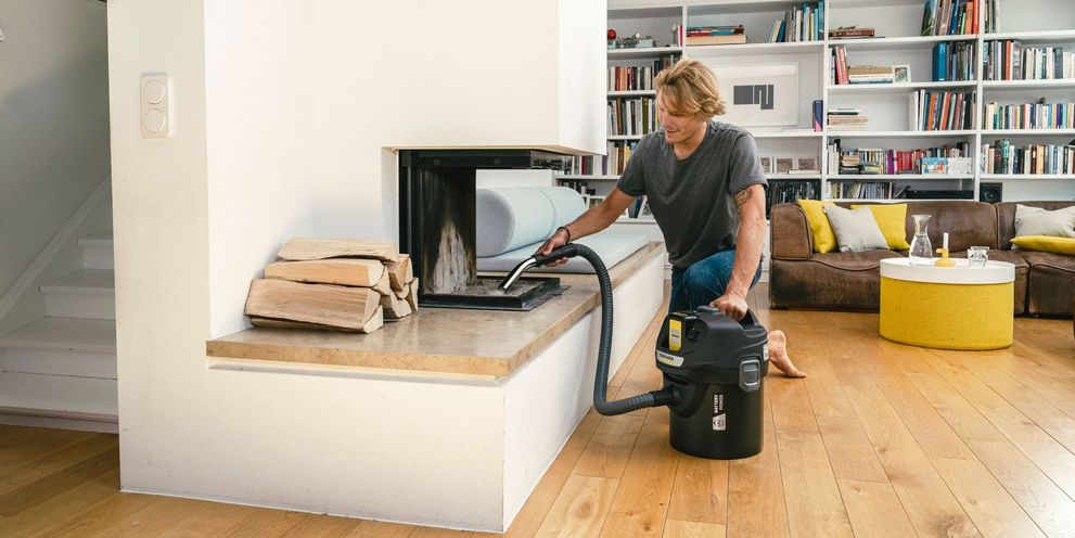 Man is vacuuming his fireplace with the Kärcher ash and dry vacuum cleaner