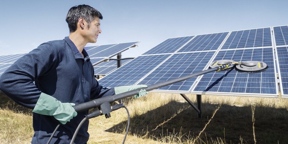 A man cleaning photovoltaic systems with a Kärcher cleaning system