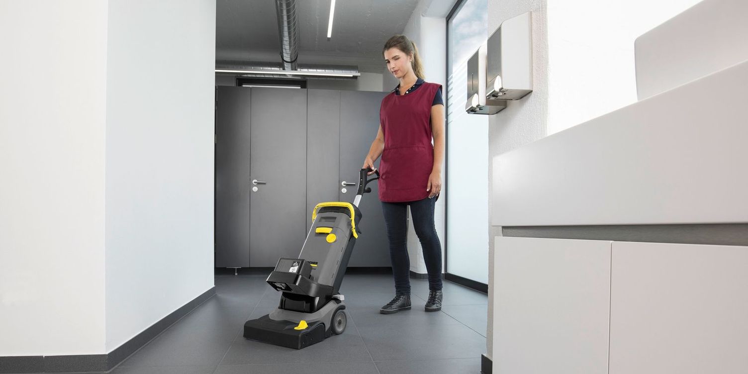 A worker cleans floors in a restroom.