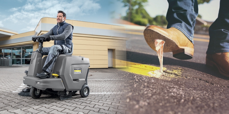 A worker uses a Kärcher ride-on floor sweeper to clean a car lot.