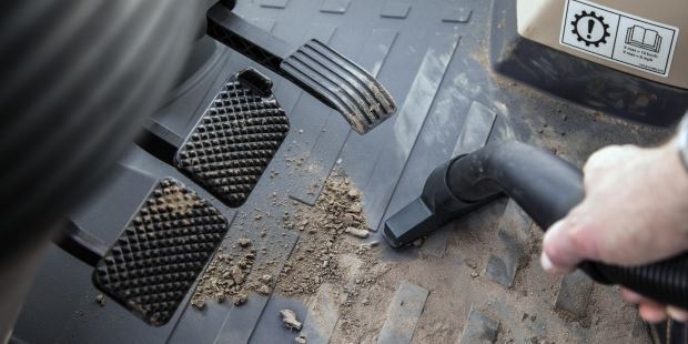 Cab Interiors A person vacuums debris from the driver area of a truck cab.