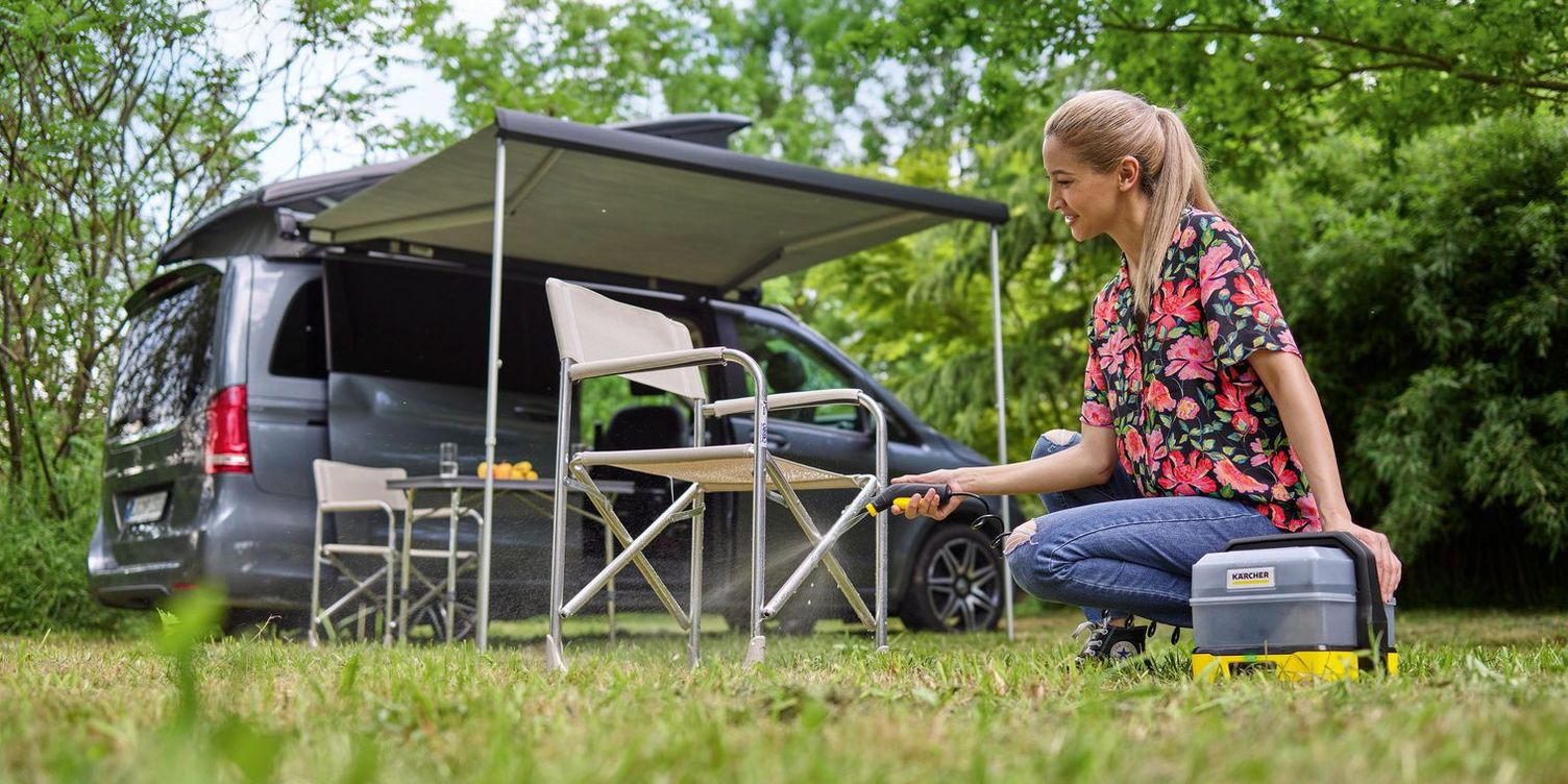 A woman sprays down camping equipment.