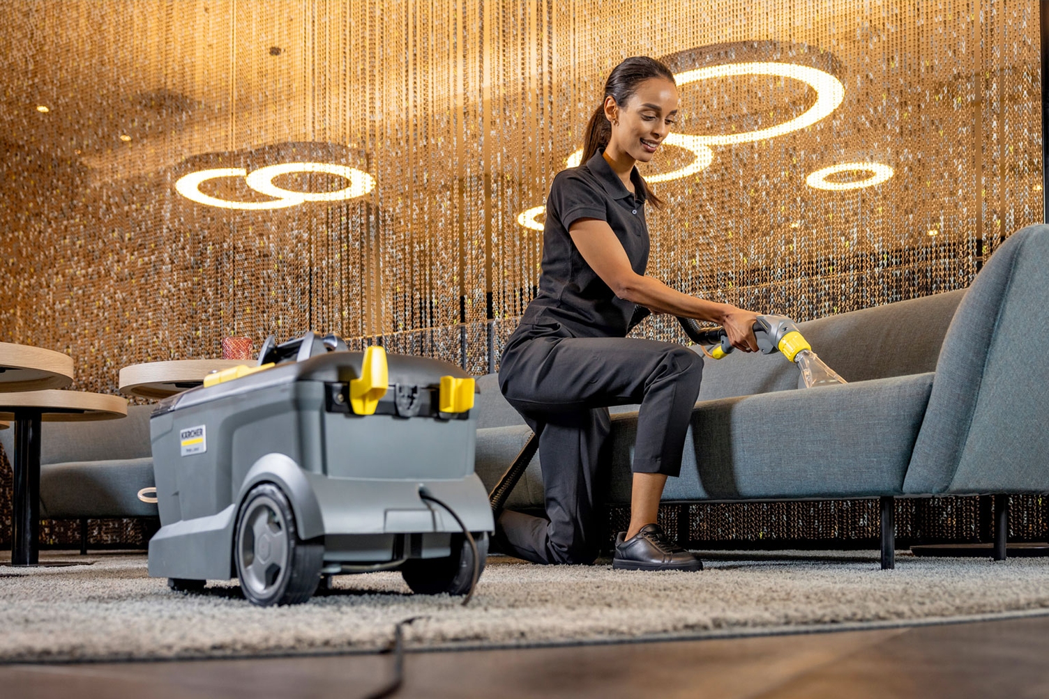 A worker uses a compact extractor to clean hotel furniture.