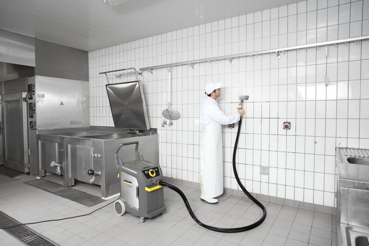 Worker using steam cleaner on tiled wall