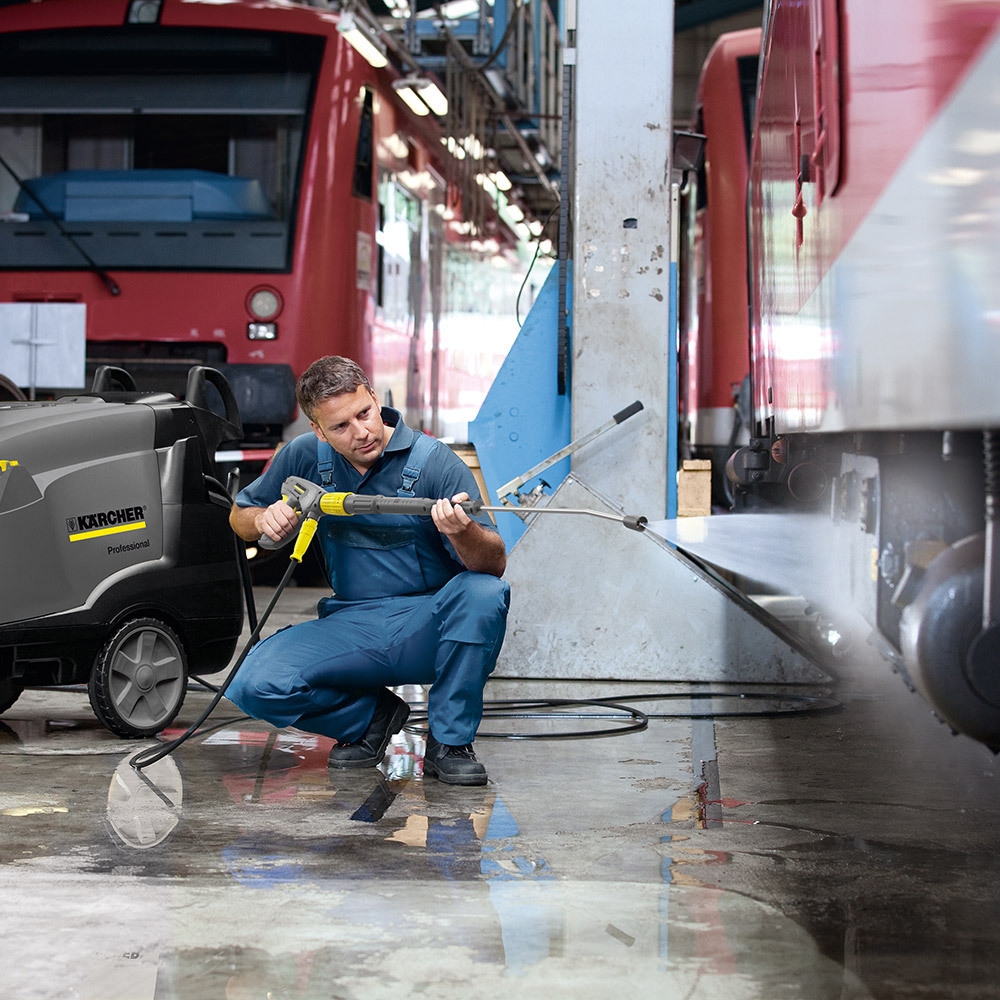 A worker pressure washes a semi truck with an electric-powered hot water pressure washer.
