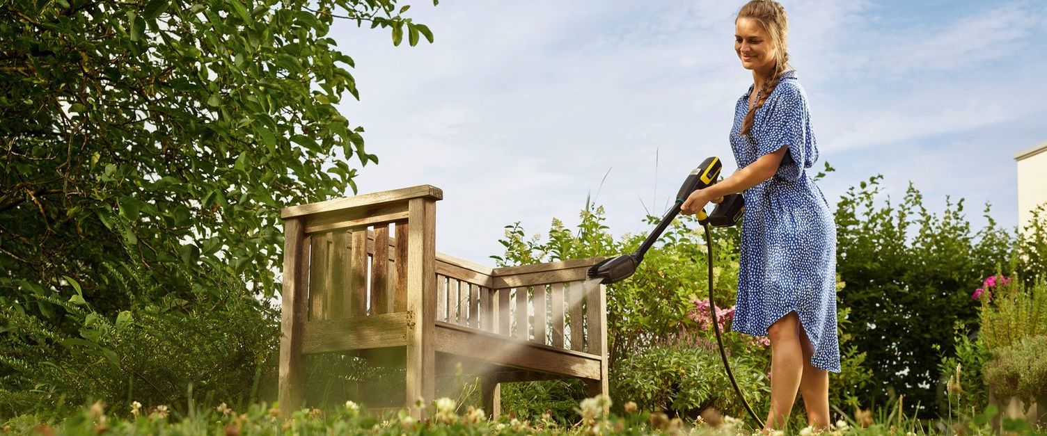 Cleaning garden furniture A woman cleans a garden bench with the Kärcher handheld cleaner