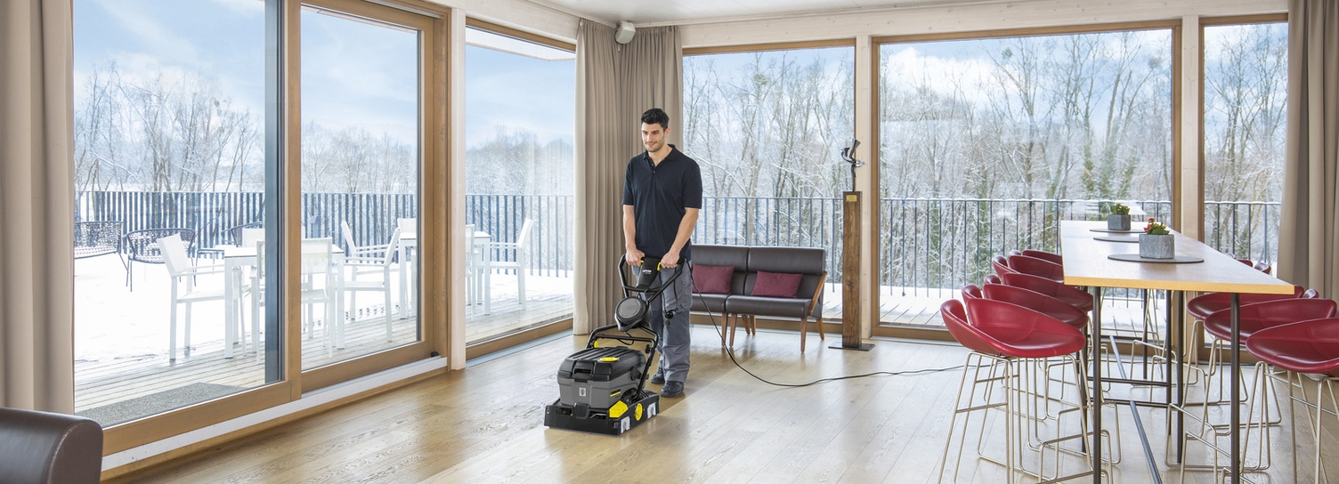 A man cleaning the floor with a Kärcher scrubber dryer