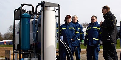 A group of workers talk as they stand next to water treatment equipment.