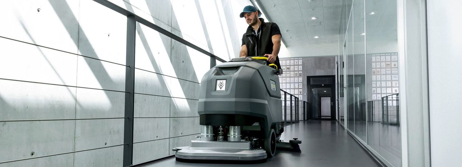 Kärcher Commercial Floor Scrubbers A man is seen cleaning a linoleum floor using a Kärcher walk-behind floor scrubber.