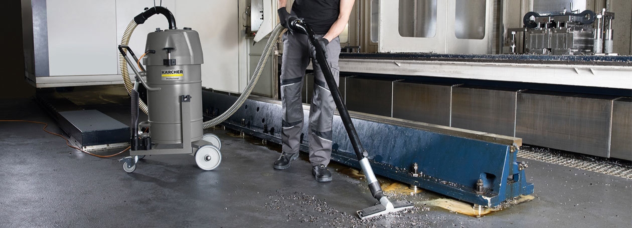 Industrial Vacuum Accessories A worker uses a Kärcher Industrial vacuum with accessories to clean fine particles off a manufacturing plant floor.