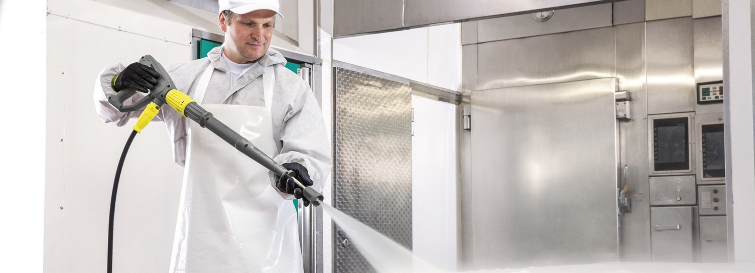 A worker uses a Kärcher hot water pressure washer to clean and disinfect a commercial kitchen.
