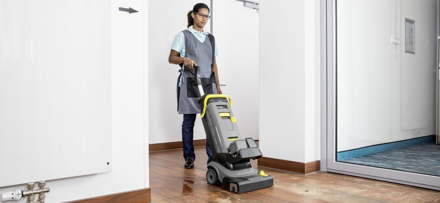 A woman maintaining a wooden floor with a scrubber dryer