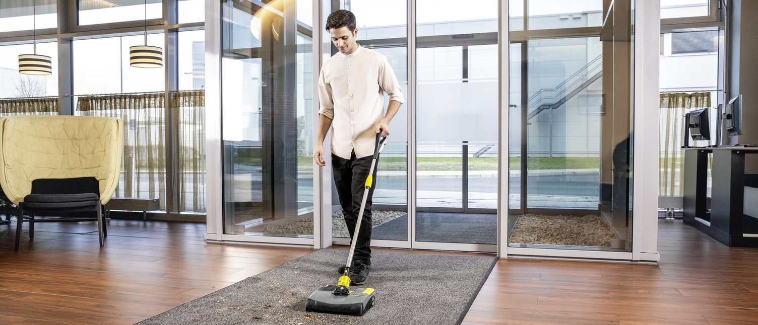 A person cleaning the entrance area of a hotel with an electric broom
