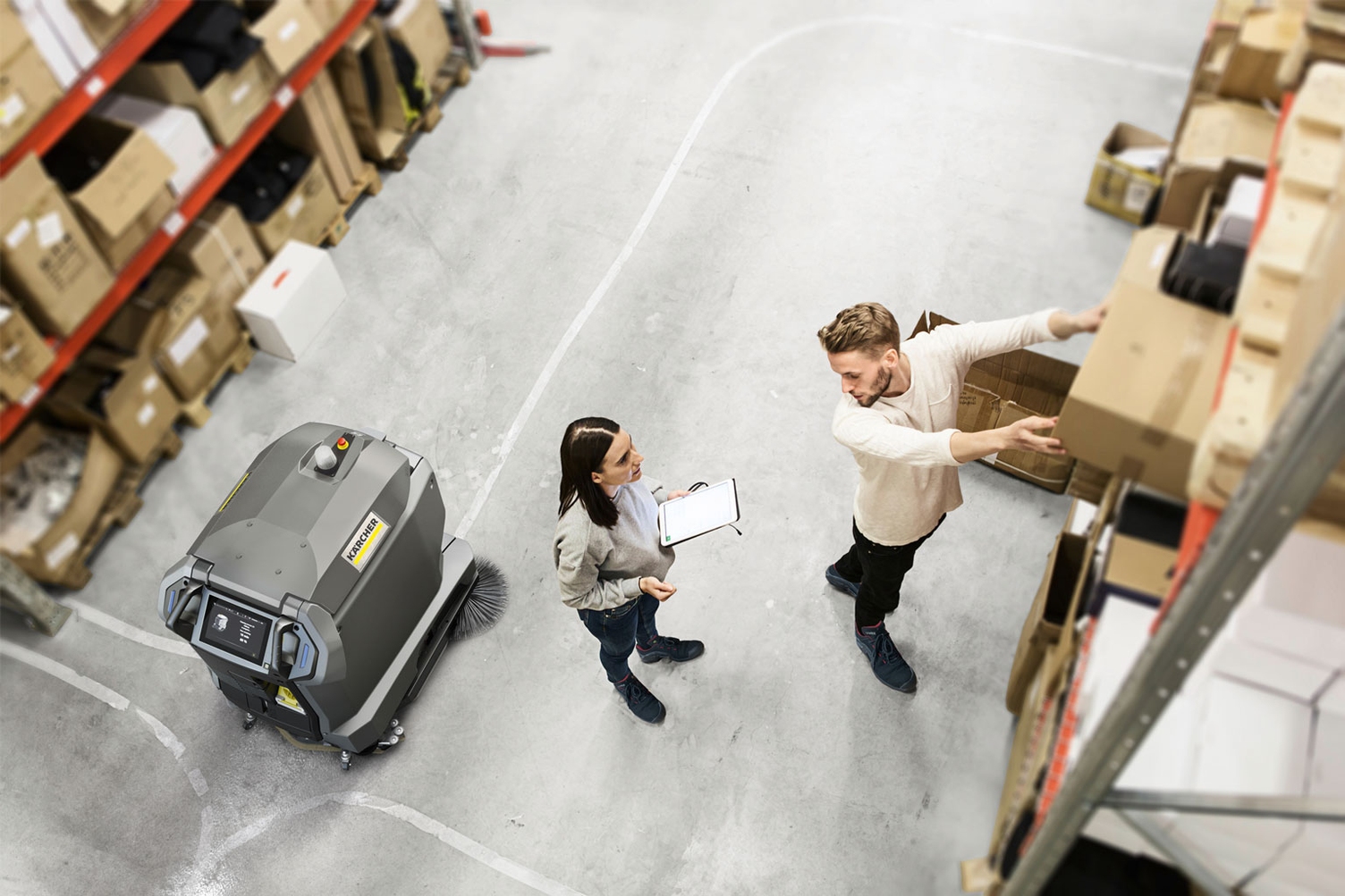 A KIRA autonomous floor scrubber maintains floors while people work around it.