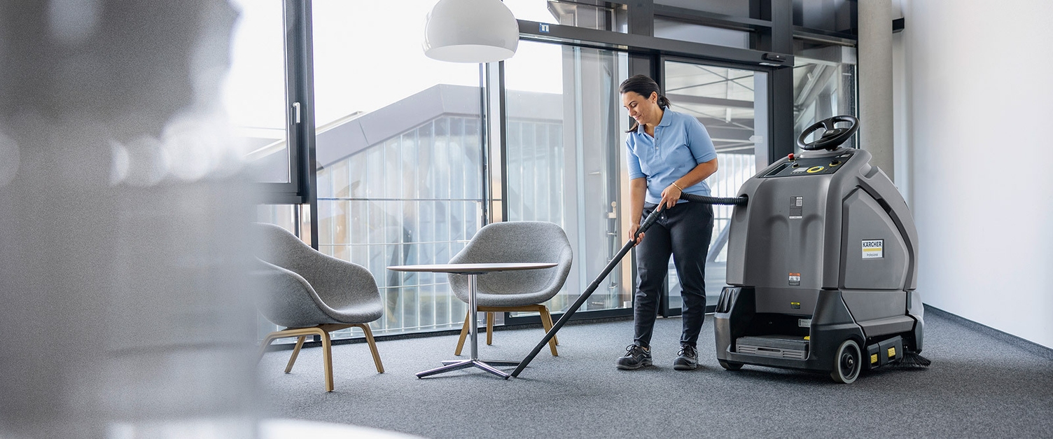 Interior cleaning in buildings A worker vacuums office carpets with the Kärcher KIRA CV 60/1 autonomous vacuum cleaner