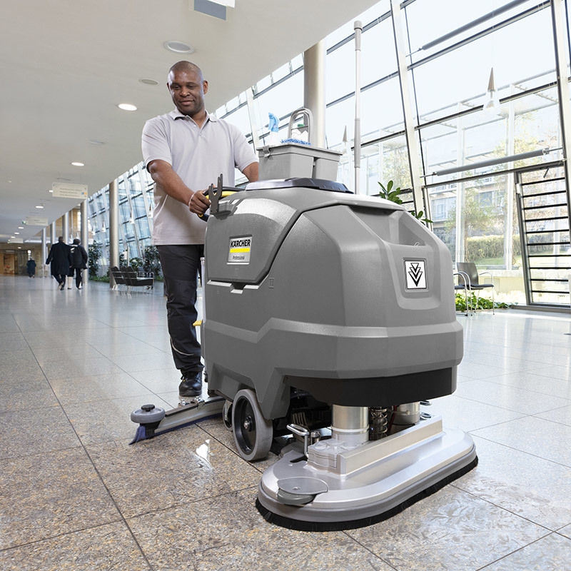 Improve Productivity with Floor Scrubbers A man cleans tiled floors with a walk-behind floor scrubber