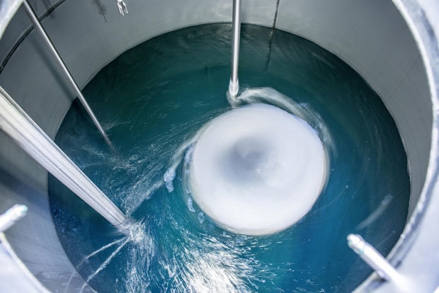 Blue liquid being mixed in a silver drum.