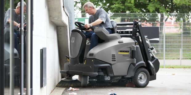 A worker cleans debris from a parking lot.