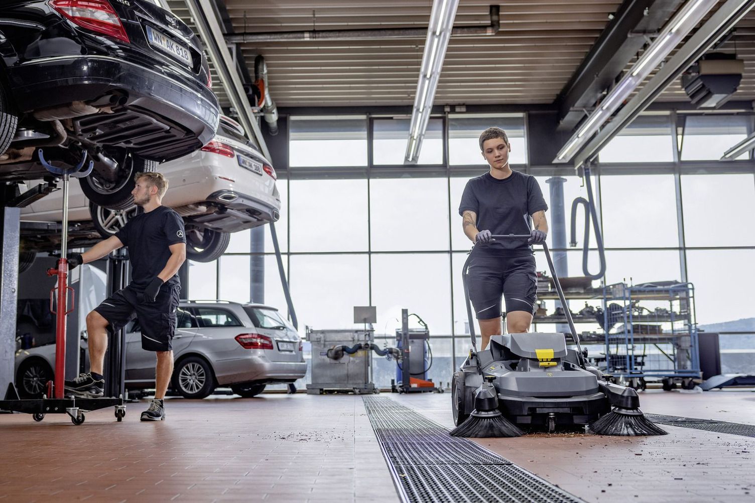 Kärcher KM 75/40 W A worker sweeps floors inside an auto repair shop.