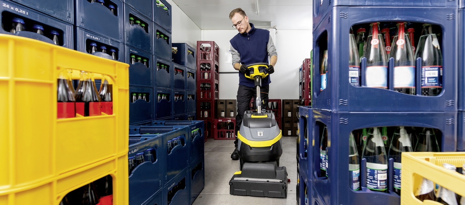 A person operates a scrubber-dryer in a cold storage room