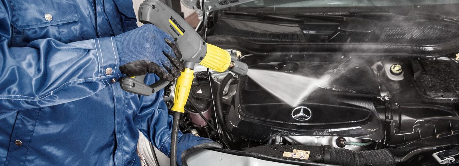 A worker pressure washes an engine compartment with a Kärcher hot water pressure washer
