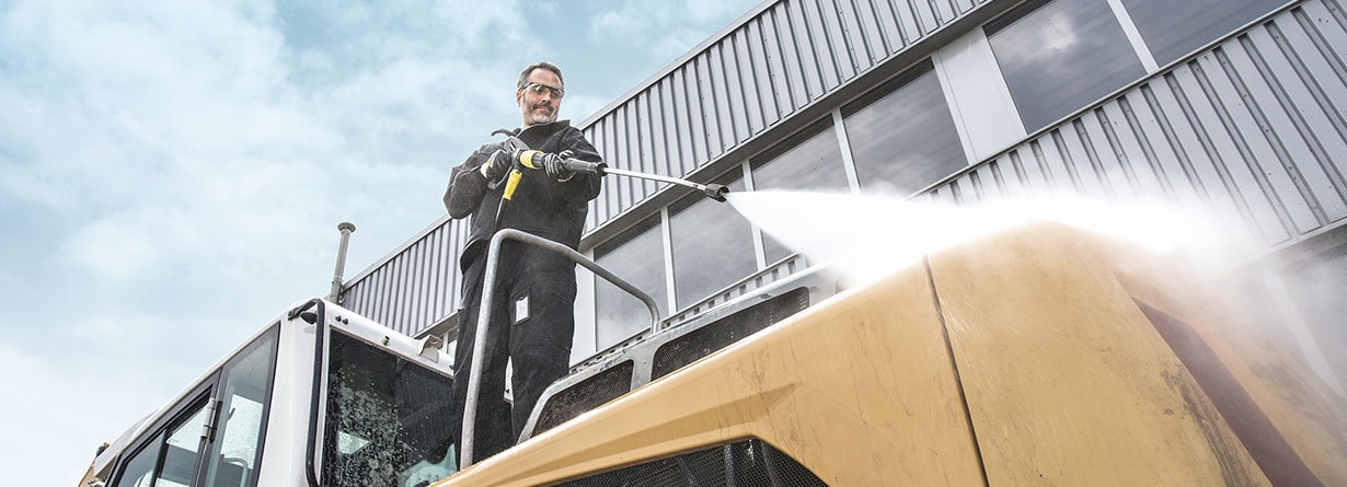 Commercial Pressure Washer Rentals A man cleans construction equipment with a rented pressure washer.