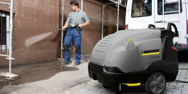 A worker pressure washes an exterior wall.