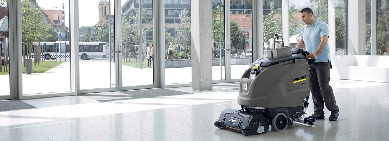 Commercial Floor Scrubber Rentals A worker uses a walk-behidn floor scrubber to clean office floors.