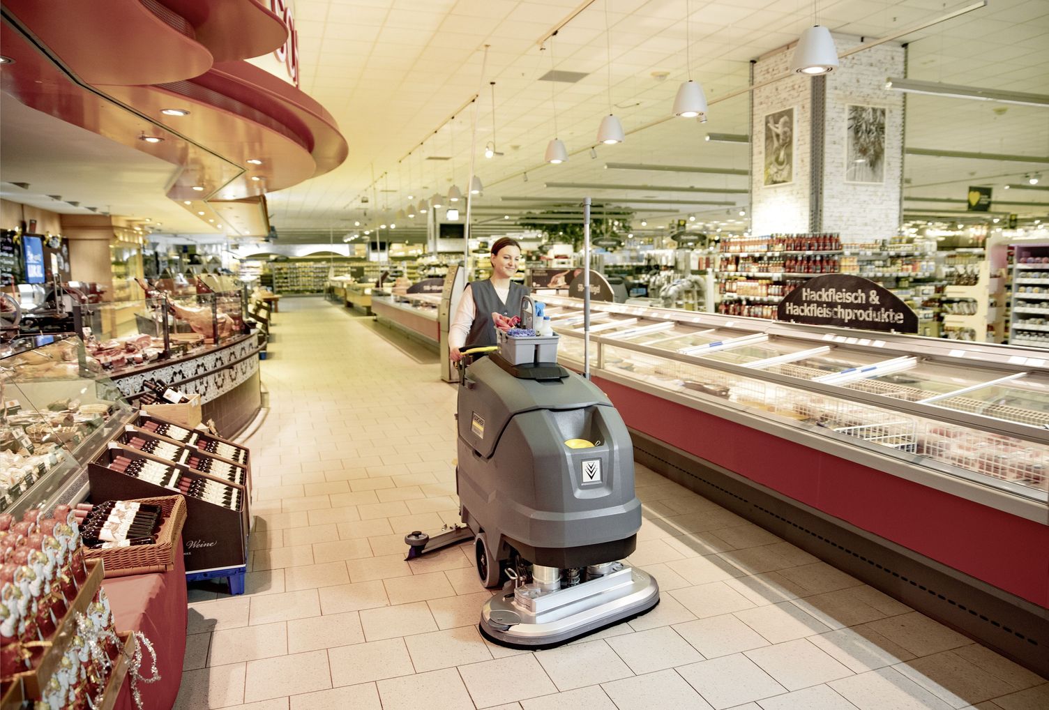 Worker cleaning supermarket with floor scrubber