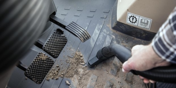 A person vacuums the interior of a tractor using a Kärcher vacuum cleaner.