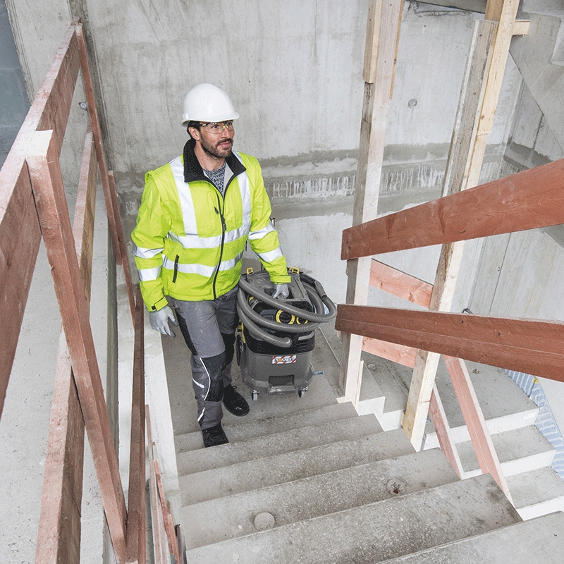 Improve Productivity by Renting a Wet/Dry Vacuum A worker walks up stairs carrying a Kärcher wet/dry vacuum.