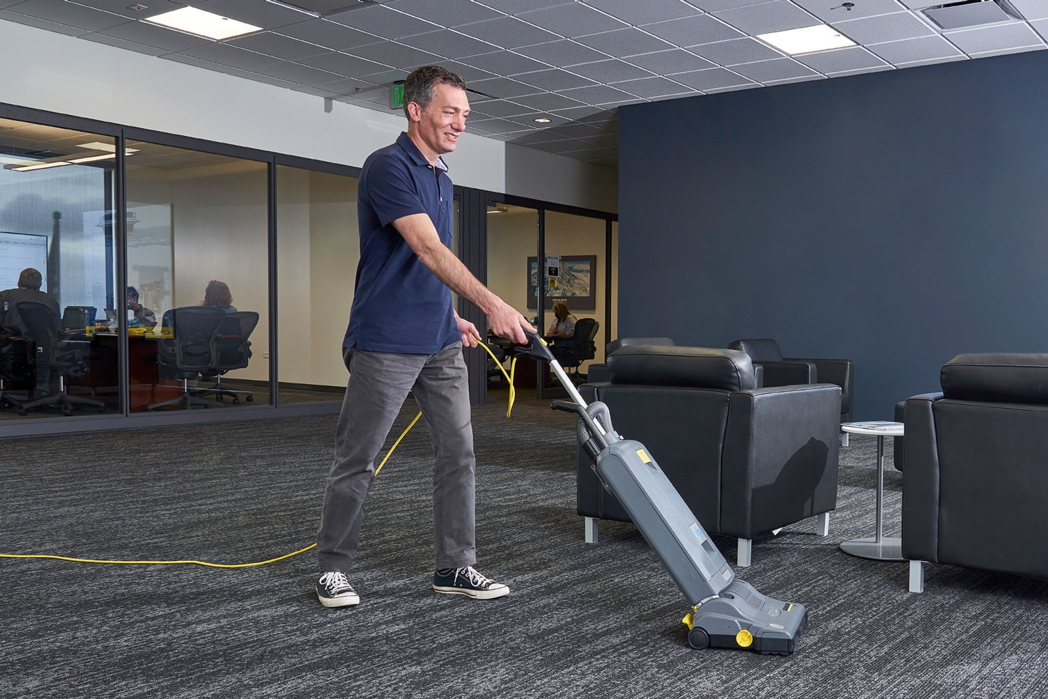A worker vacuums carpets inside an office complex.