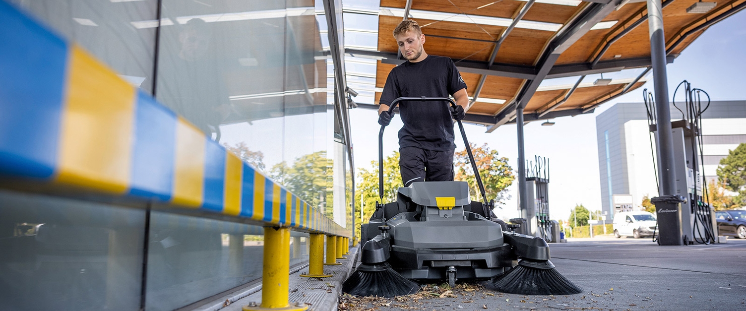 Walk-Behind Commercial Floor Sweepers A worker uses a walk-behind commercial floor sweeper to pick up leaves and debris.