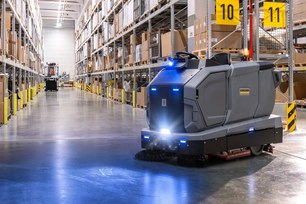 A robotic floor scrubber cleans floors inside a warehouse.