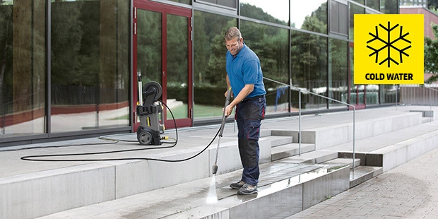 Man cleaning outdoor stairs with an electric cold water pressure washer.
