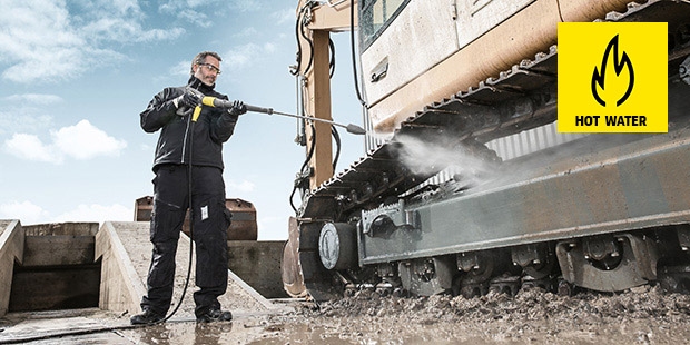 Man cleaning dirty excavator with a hot water pressure washer.