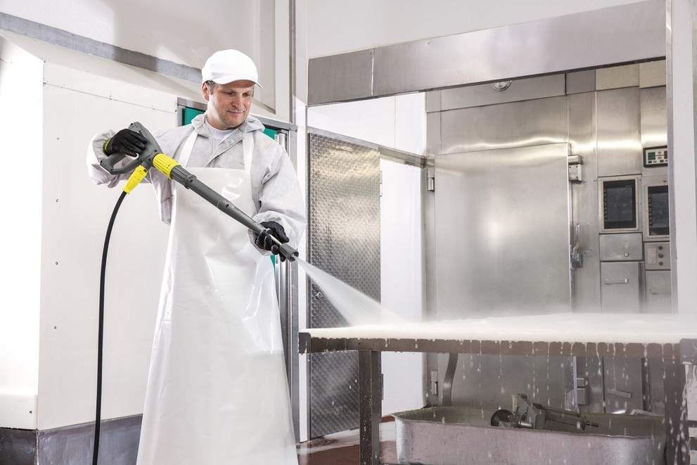A worker cleans a commercial kitchen with a Kärcher electric-powered hot water pressure washer.