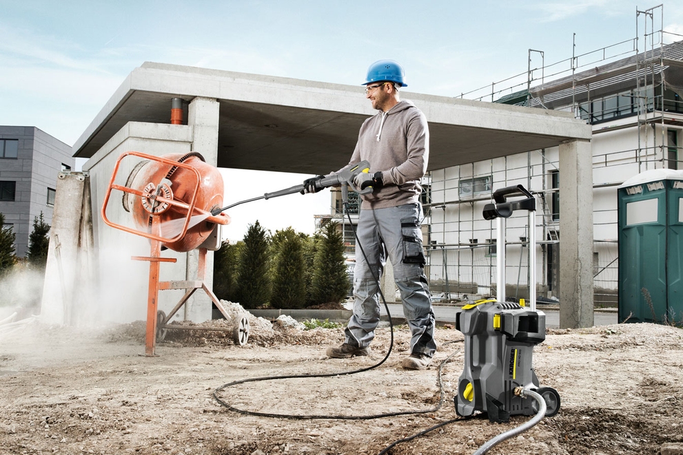 A worker cleans a cement mixer with an electric-powered cold water pressure washer.