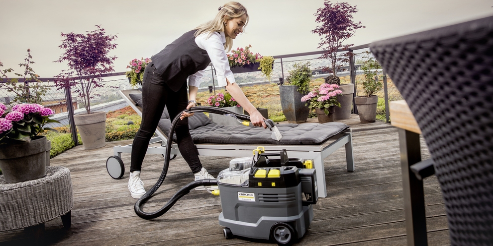Cleaning Upholstery With Extractors A person cleans a lounge chair outside with a Kärcher carpet and upholstery extractor.