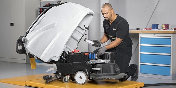 A service technician repairs a floor scrubber.