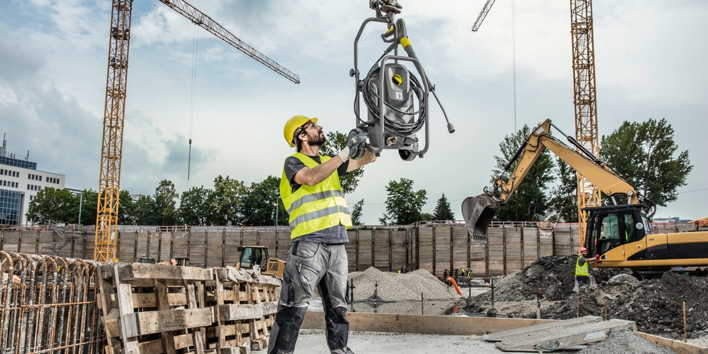 A worker transports a Kärcher commercial pressure washer to a construction jobsite.